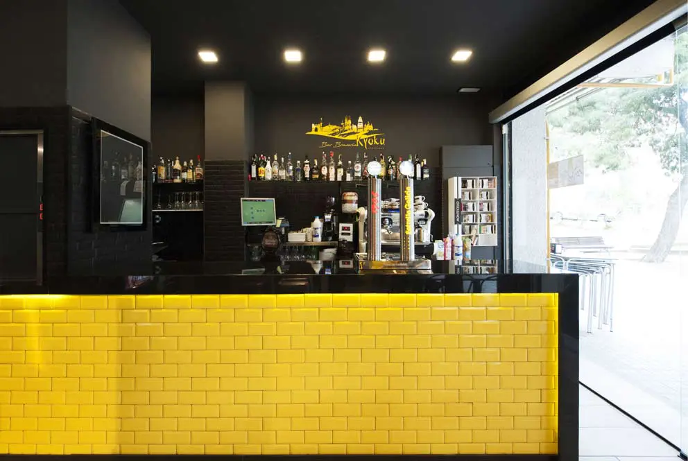 Barra bar rajoles groc brillant amb marc en negre. Disseny Sincro