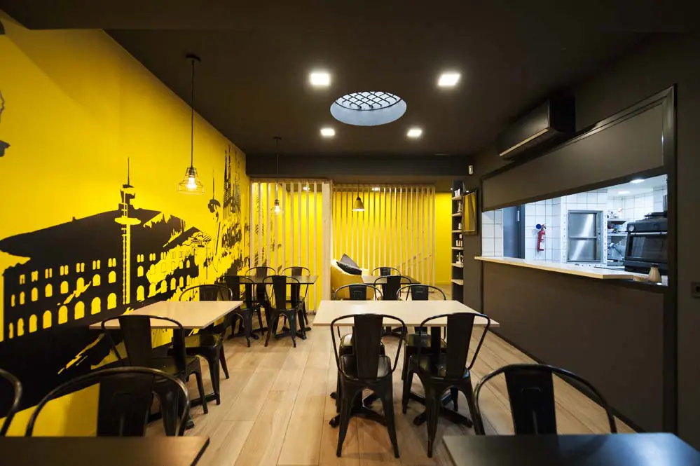 zona de taules restaurant color negre i groc.