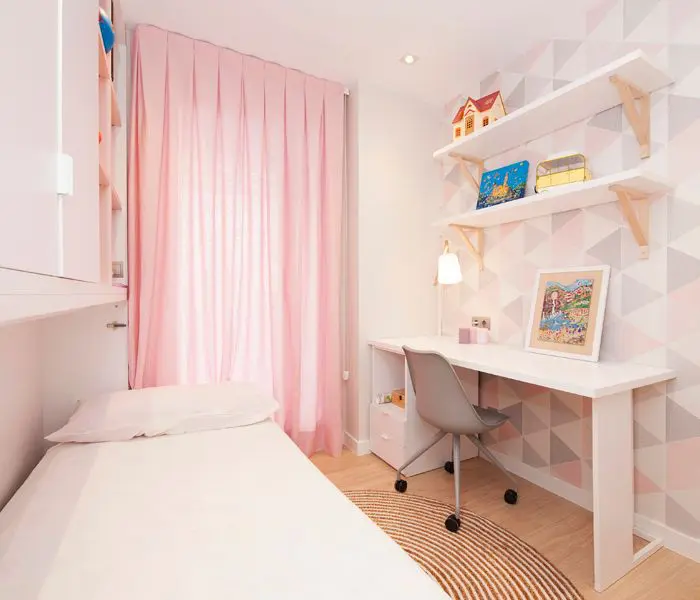Dormitorio juvenil chica con papel pintado geométrico rosa y mobiliario: escritorio, silla, mueble cama abatible.