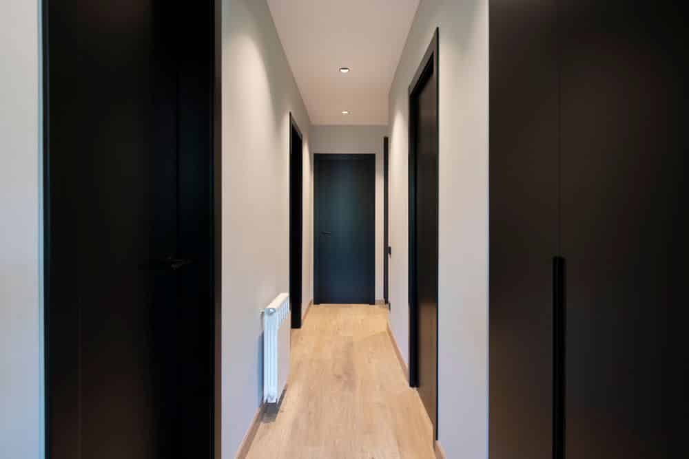 Pasillo con las puertas de color negro y pintura pared gris claro. Reforma de piso en Barcelona