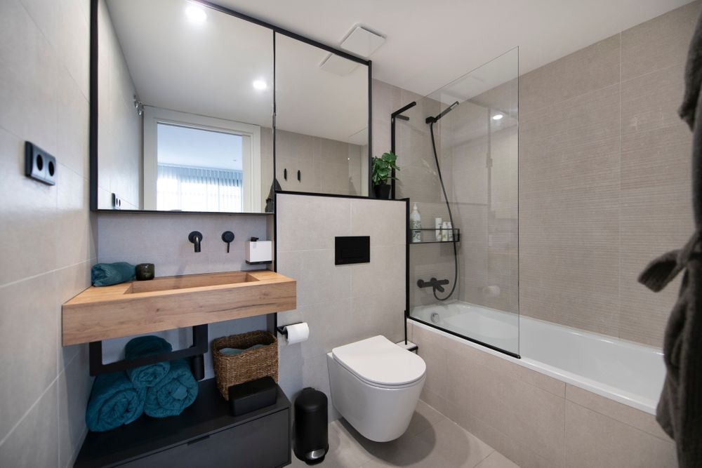 Bany amb banyera amb moble alt amb mirall amb marc negre