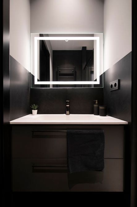 Mueble suspendido negro con dos cajones con lavabo blanco integrado y espejo con luz