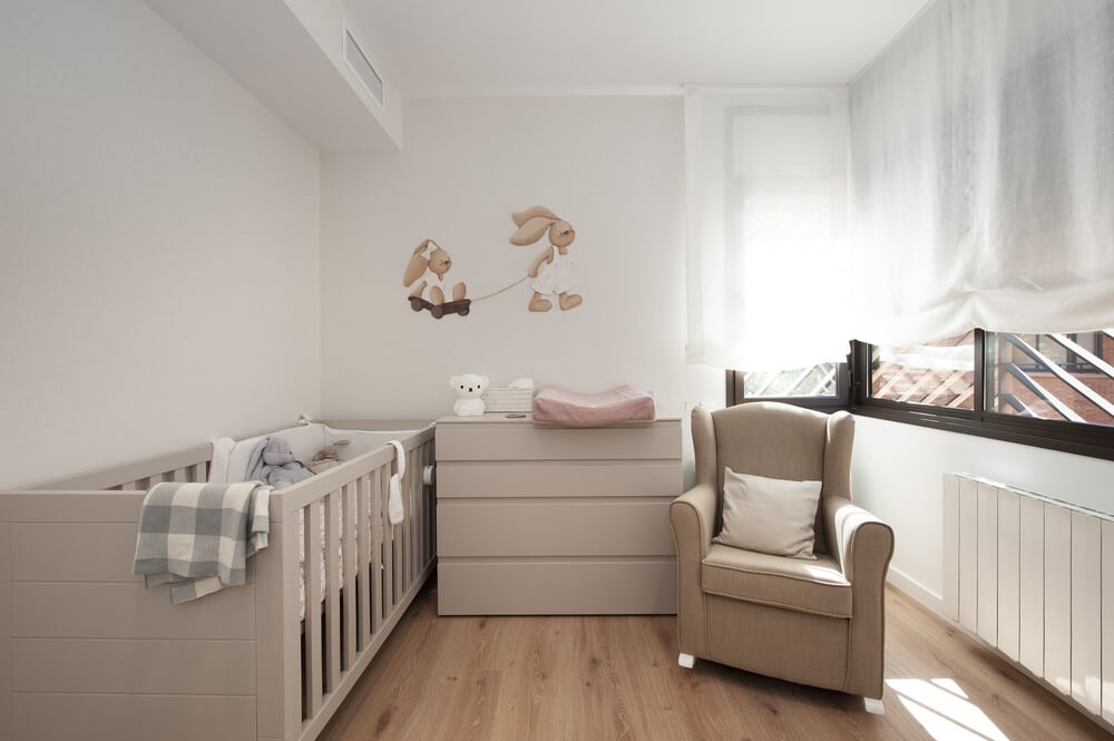 Dormitorio infantil con cuna en acabado beige arena. Con vinilos de conejos. Estilo clásico.