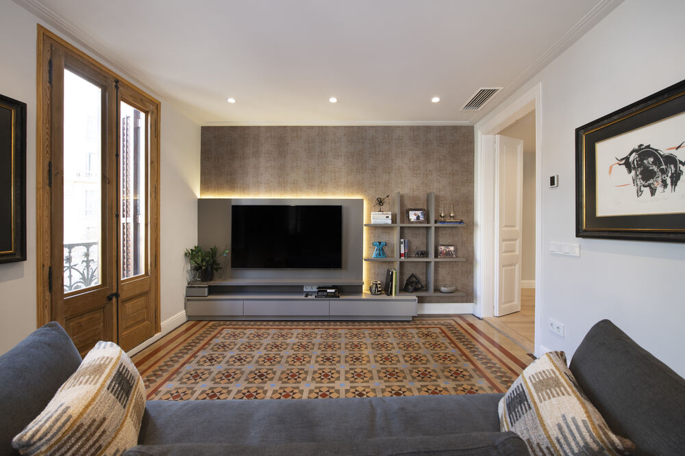 Zona de TV con mueble retroiluminado con alfombra mosaico Nolla. Piso Eixample Dreta Barcelona.