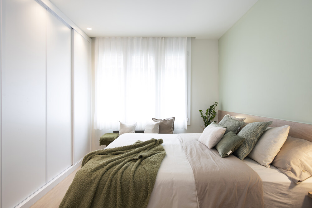 Dormitorio principal con tonalidades naturales en pintura y téxtiles. Beige, marrones, verde, madera, etc. Con cortinas convencionales.