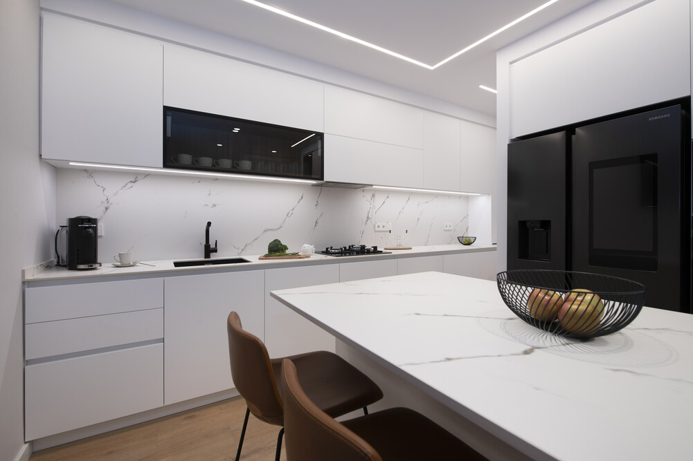 Mueble de cocina y encimera en tonalidad blanco, con algunos elementos en negro.