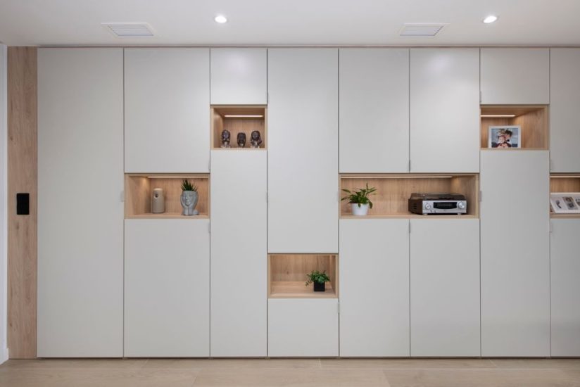 armario empotrado en el salón con huecos de madera decorativos. Con mucho almacenaje