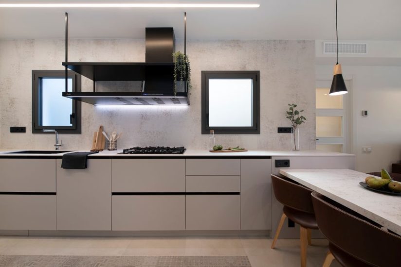 Encimera y frontal Dekton nillum industrial. Y campana decorativa de grandes dimensiones de la marca Pando. Con dos estantes y acabado en negro.