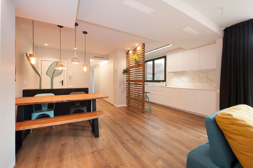 Cocina blanca con encimera y salpicadero de marmol abierta al salón comedor.