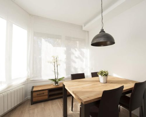 Mesa, sillas y lámpara colgante en comedor estilo nórdico industrial.