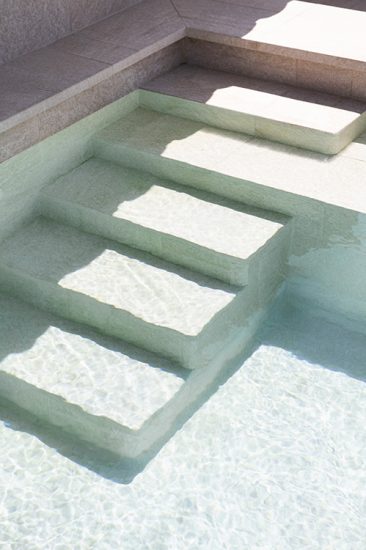 Escalera de obra de la piscina en color beig efecto piedra natural. Reforma de piscina en Barcelona.