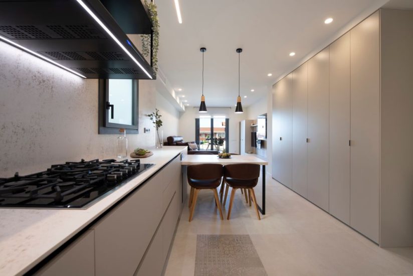 Cocina abierta con mesa de comedor de península que hace de separador con el salón