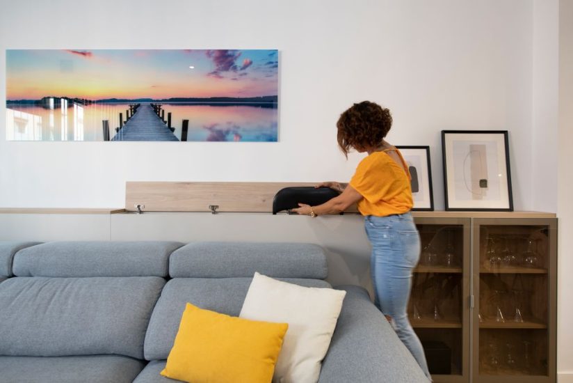 Mueble detrás del sofá para guardar sillas y mesas plegables en el salón