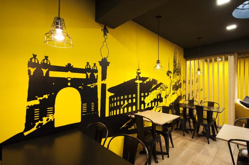 Pared con vinilo skyline barcelona en color amarillo y negro en una de las paredes de la zona de mesas. Restaurante Kyoku