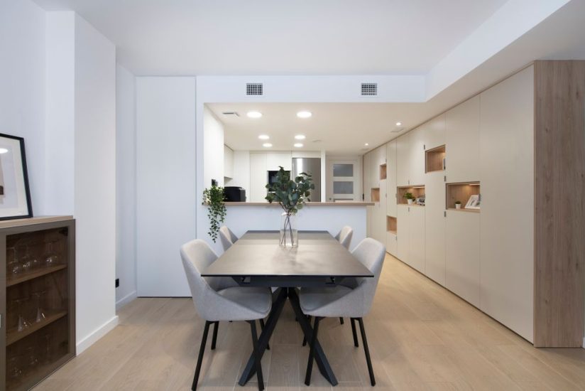 Zona de comedor con mesa rectangular negra y sillas en gris patas negras
