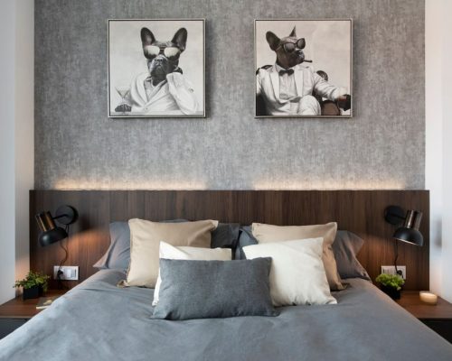 capçal de llit fusta fosca i paret amb paper pintat gris desgastat. Quadres de gossos divertits