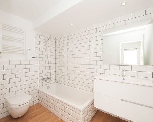 Cuarto de baño con baldosa tipo metro blanca y juntas negras.