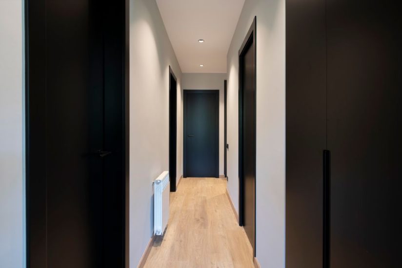Passadís amb les portes de color negre i pintura paret gris clar. Reforma de pis a Barcelona