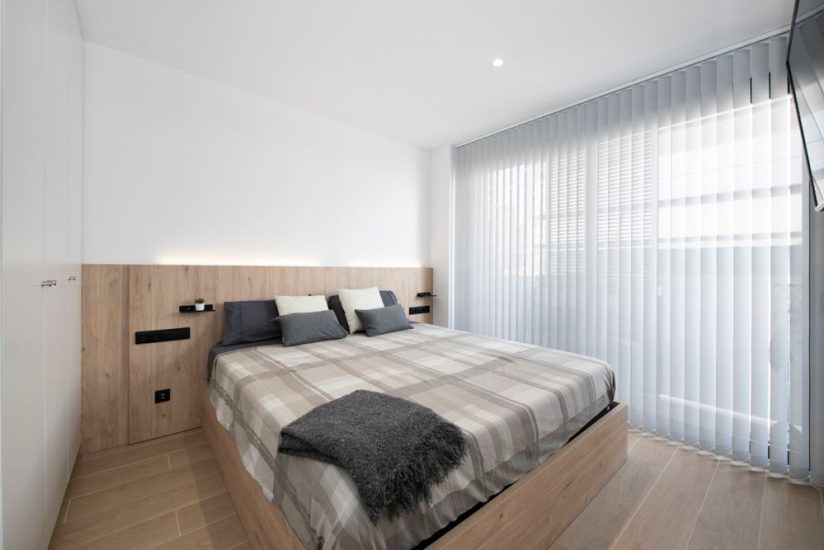 Canapé y cabecero de madera tono claro en dormitorio principal
