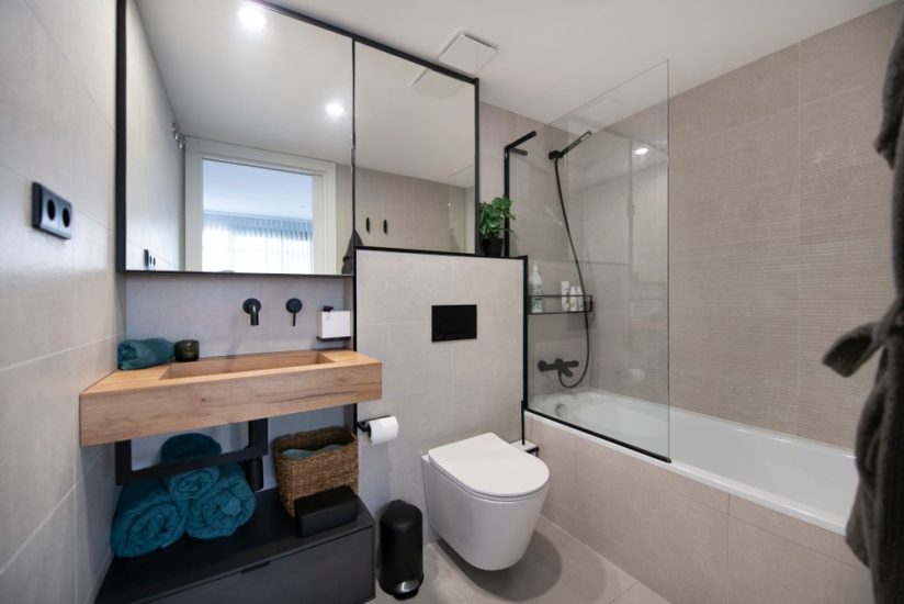 Baño con bañera con mueble alto con espejo con marco negro