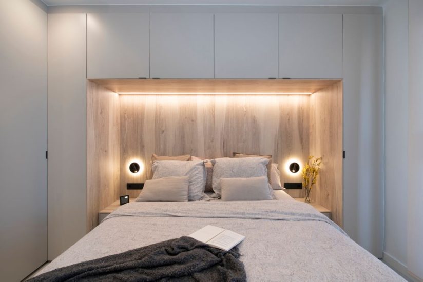 Mueble en arco que envuelve el cabezal de la cama. En tono gris claro y maderas claro y madera