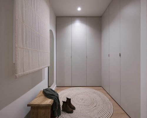Armari en forma L de vestidor al dormitori principal en tonalitats sorra