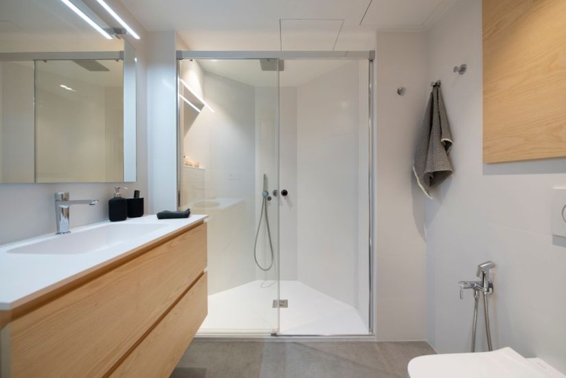 Bany blanc i fusta amb dutxa amb diversos costats per la forma rara de l'immoble