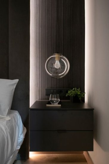 Llum penjant amb esfera transparent sobre tauleta de nit negra