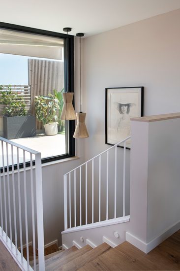 Escalera de madera con barandilla de hierro en blanco de un ático dúplex en Barcelona.